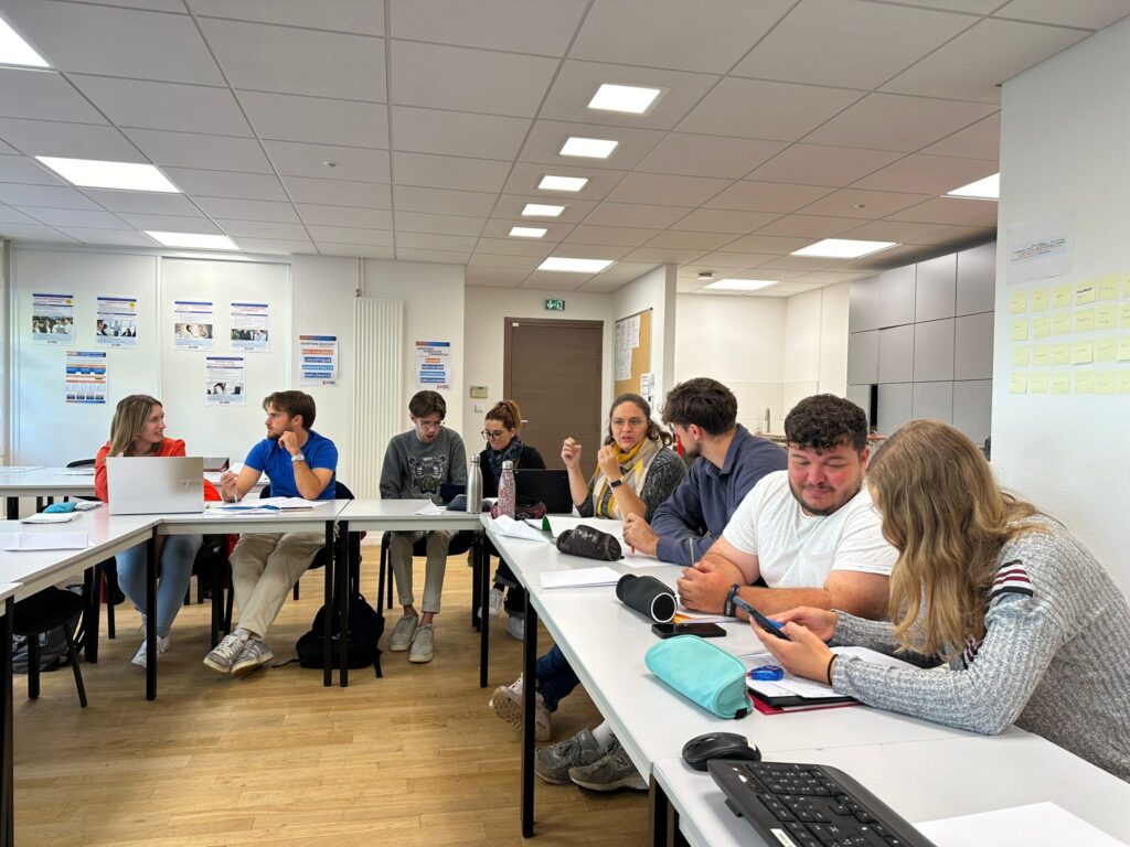 Un groupe d'apprenants réunis autour de tables de travail dans une salle de classe lumineuse lors d'une session de formation chez Perf Form.